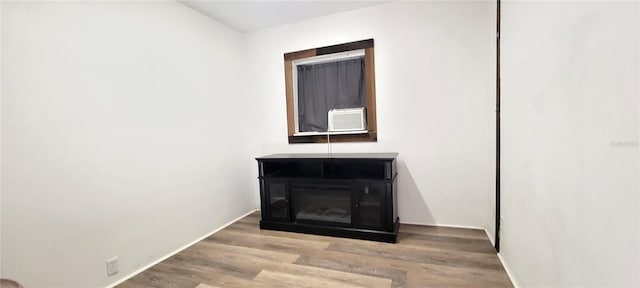 room details with cooling unit, a wood stove, baseboards, and wood finished floors