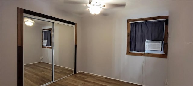 unfurnished bedroom featuring ceiling fan, a closet, cooling unit, and wood finished floors