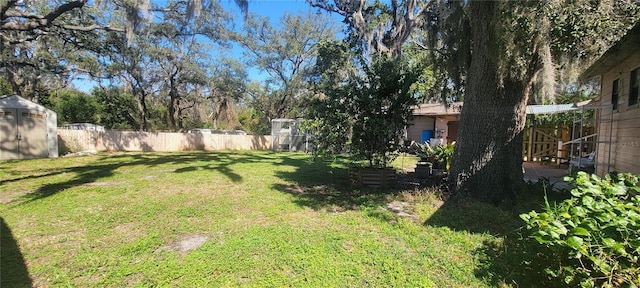 view of yard featuring a fenced backyard, an outbuilding, and a shed