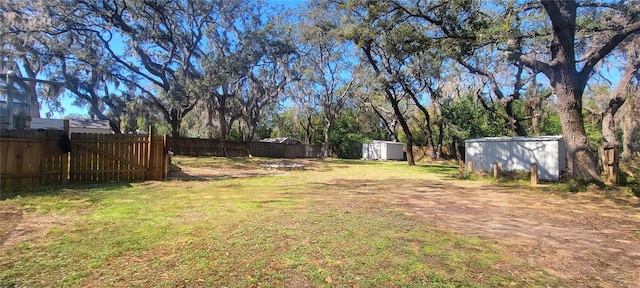 view of yard featuring a fenced backyard, a storage unit, and an outbuilding