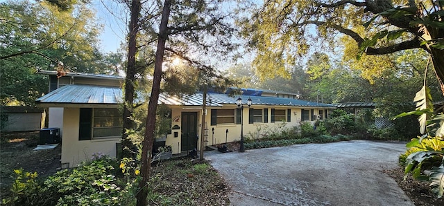 view of front facade featuring metal roof, driveway, and stucco siding