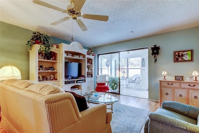 living room with a textured ceiling, light wood finished floors, and a ceiling fan