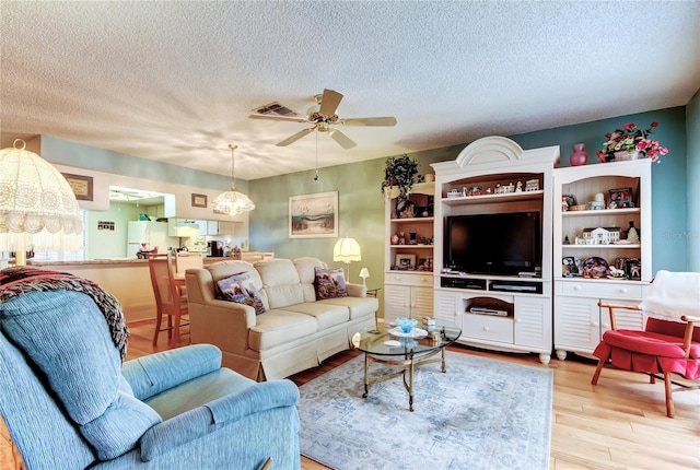 living area featuring a textured ceiling, wood finished floors, and a ceiling fan