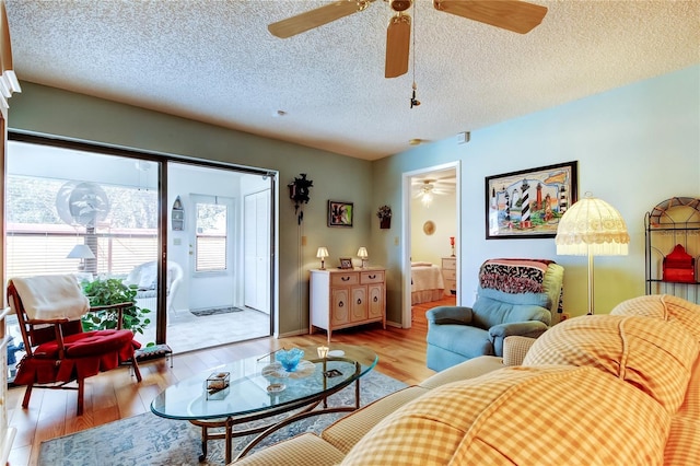 living area featuring a textured ceiling, ceiling fan, light wood-type flooring, and baseboards