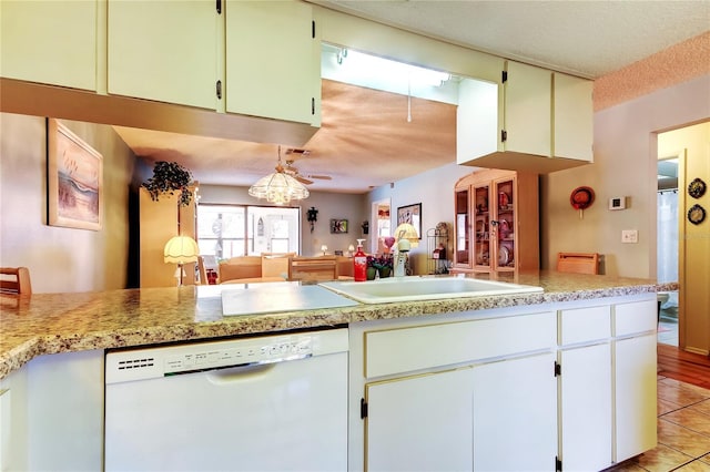 kitchen featuring light tile patterned floors, white dishwasher, light countertops, a textured ceiling, and a sink