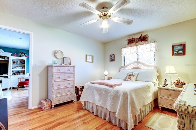 bedroom featuring light wood-style floors, a textured ceiling, baseboards, and a ceiling fan