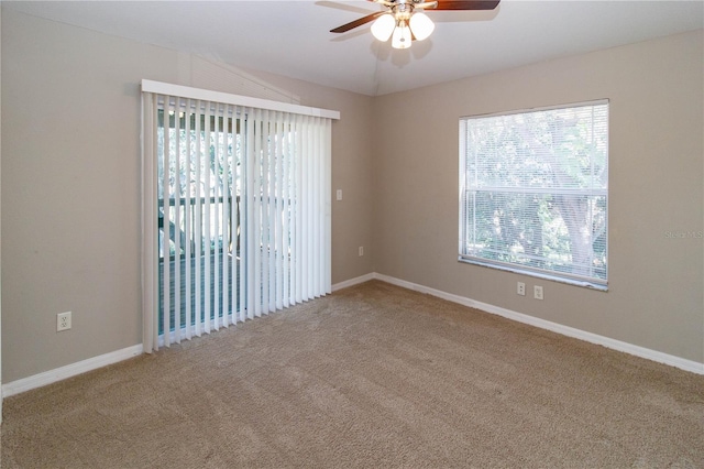 carpeted spare room featuring lofted ceiling, a healthy amount of sunlight, ceiling fan, and baseboards