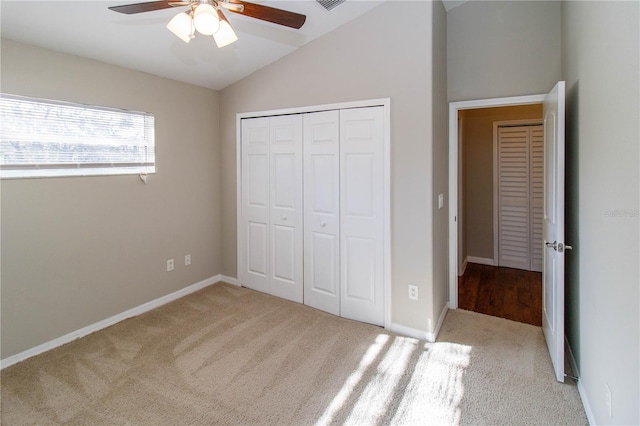 unfurnished bedroom featuring a closet, light carpet, vaulted ceiling, ceiling fan, and baseboards