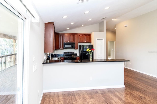 kitchen featuring dark countertops, lofted ceiling, light wood-style flooring, a peninsula, and black appliances