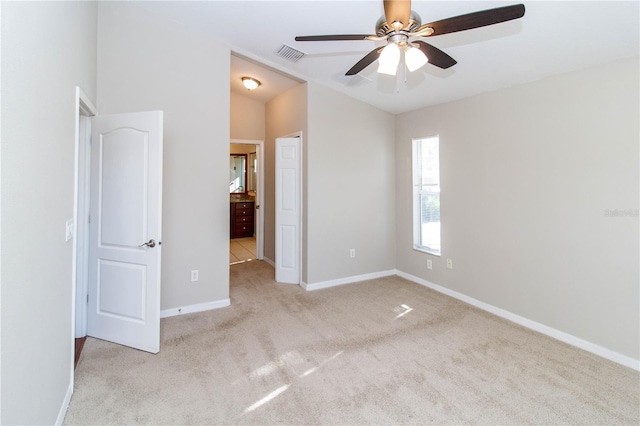 unfurnished bedroom with lofted ceiling, light colored carpet, visible vents, baseboards, and ensuite bath