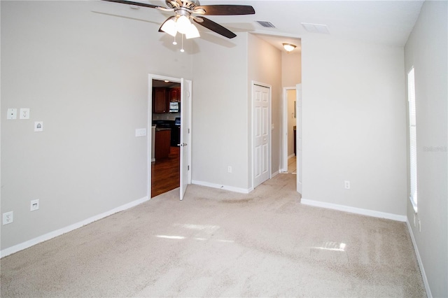 unfurnished bedroom with baseboards, visible vents, a ceiling fan, and light colored carpet