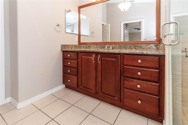 full bath with tile patterned flooring, baseboards, a tile shower, and vanity