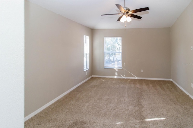 carpeted spare room featuring ceiling fan and baseboards