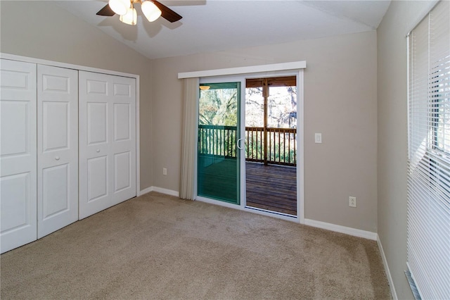 unfurnished bedroom featuring lofted ceiling, light colored carpet, baseboards, access to exterior, and a closet