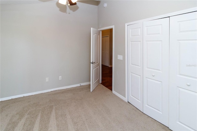 unfurnished bedroom with ceiling fan, baseboards, a closet, and light colored carpet