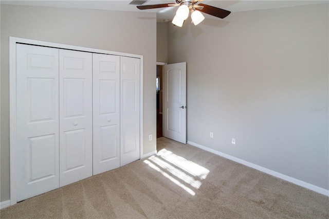 unfurnished bedroom featuring a closet, light colored carpet, vaulted ceiling, ceiling fan, and baseboards