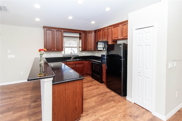 kitchen with a peninsula, a sink, visible vents, light wood-style floors, and black appliances