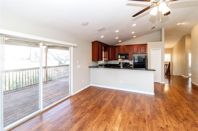 kitchen featuring dark countertops, visible vents, wood finished floors, a peninsula, and black appliances