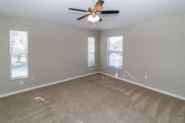 carpeted spare room with a ceiling fan and baseboards