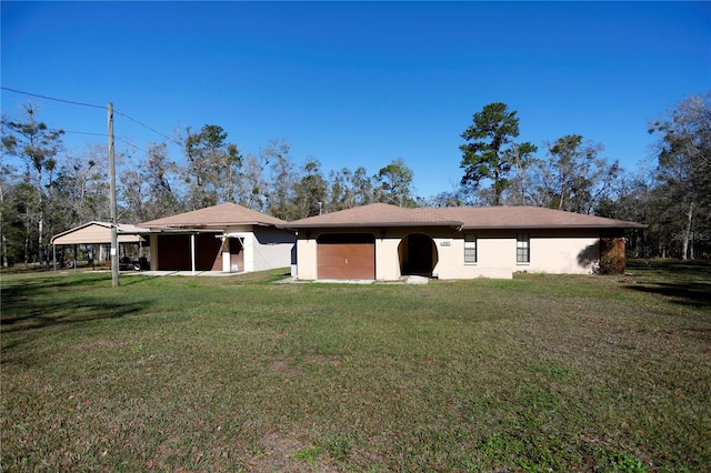 back of house with a garage, a yard, and stucco siding