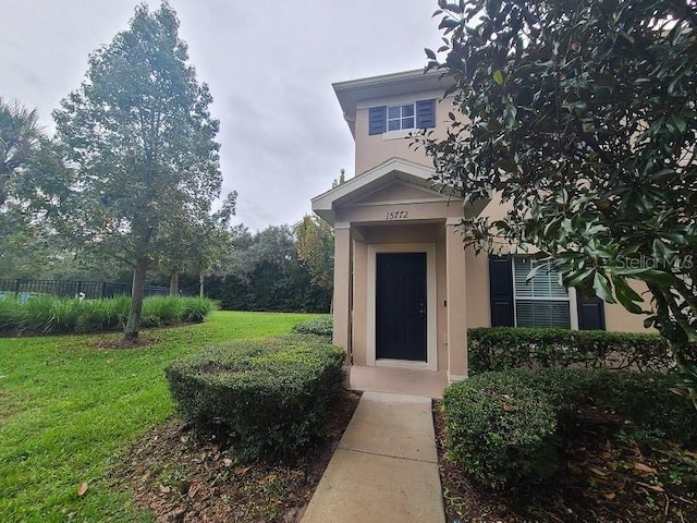 entrance to property featuring a lawn and stucco siding