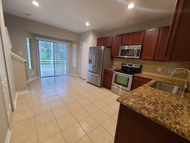 kitchen featuring stone countertops, recessed lighting, a sink, appliances with stainless steel finishes, and backsplash