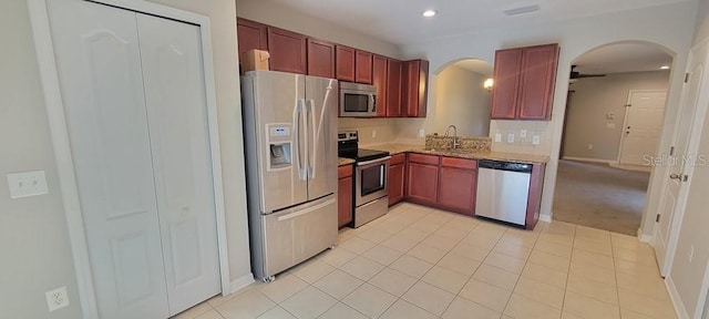 kitchen featuring arched walkways, dark brown cabinets, appliances with stainless steel finishes, and decorative backsplash