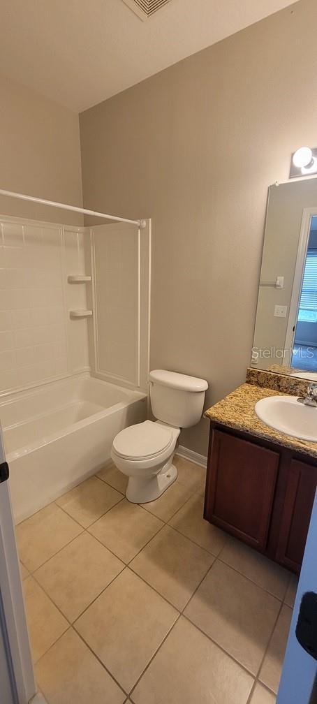 full bath featuring toilet, tile patterned flooring, tub / shower combination, and vanity