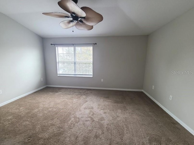 empty room with ceiling fan, baseboards, and dark carpet