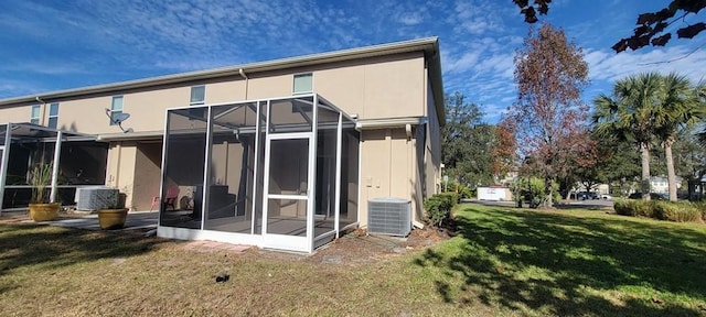 rear view of house with a sunroom, a lawn, and central air condition unit