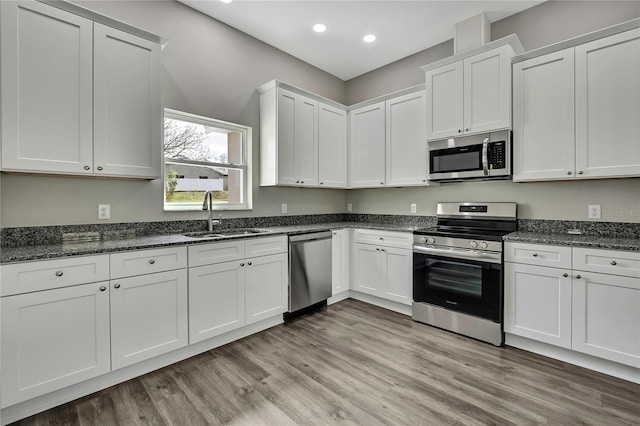 kitchen featuring light wood-style floors, appliances with stainless steel finishes, white cabinets, and a sink