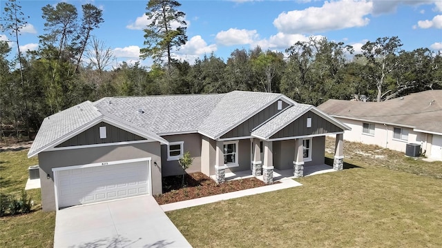 craftsman house with central air condition unit, a garage, driveway, a front lawn, and board and batten siding