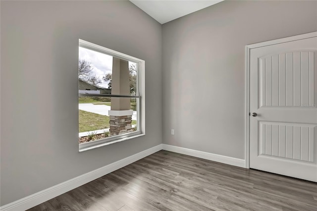 spare room with baseboards and wood finished floors