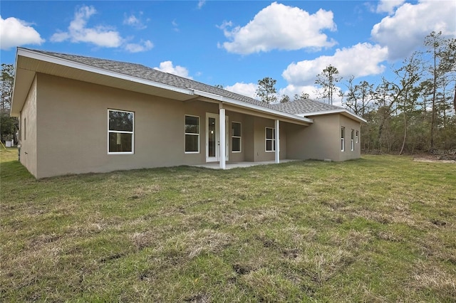 back of house with a patio, a lawn, roof with shingles, and stucco siding