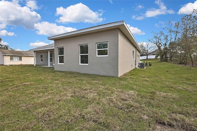 back of house with central AC, a yard, and stucco siding