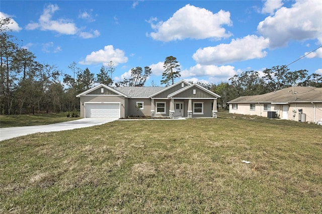 view of front of home featuring cooling unit, a garage, covered porch, driveway, and a front yard