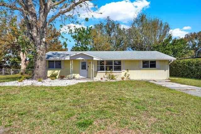 ranch-style home featuring fence and a front lawn