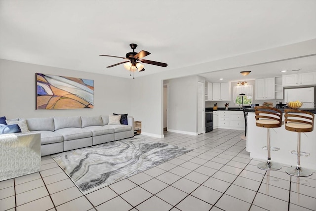 living room with ceiling fan, baseboards, and light tile patterned floors