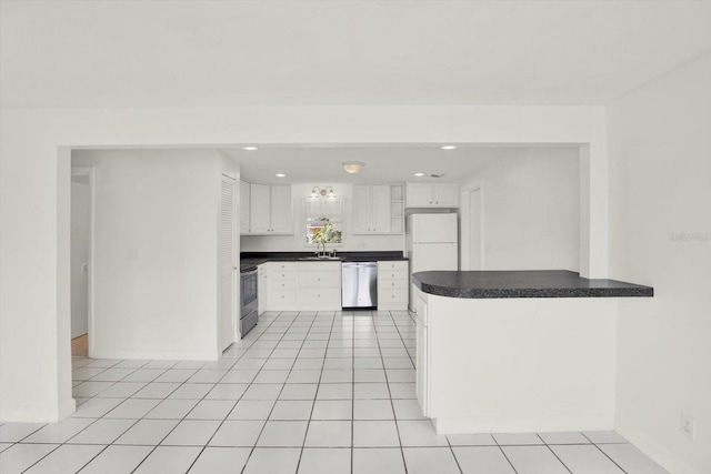 kitchen featuring light tile patterned floors, white cabinets, dark countertops, a peninsula, and stainless steel appliances