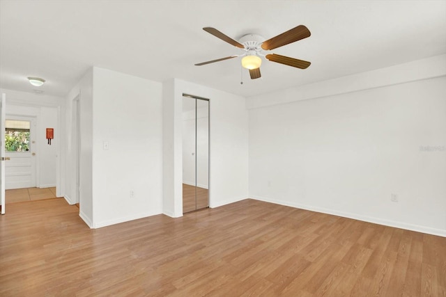 spare room featuring a ceiling fan, light wood-style flooring, and baseboards