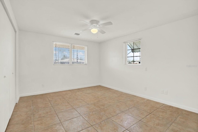 spare room with ceiling fan, visible vents, and baseboards