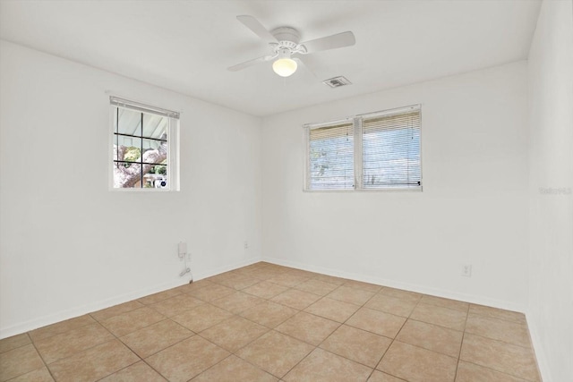 empty room featuring a ceiling fan, visible vents, baseboards, and light tile patterned floors