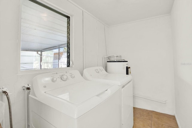 washroom with water heater, laundry area, light tile patterned floors, and washer and clothes dryer