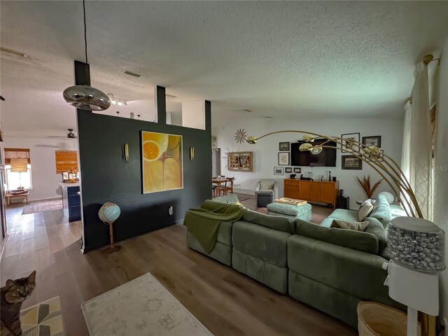 living room with visible vents, a textured ceiling, ceiling fan, and wood finished floors