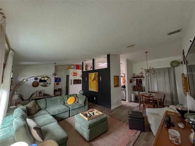 living area with visible vents, lofted ceiling, a textured ceiling, and wood finished floors