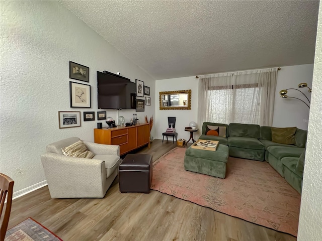 living room featuring a textured ceiling, lofted ceiling, a textured wall, and wood finished floors