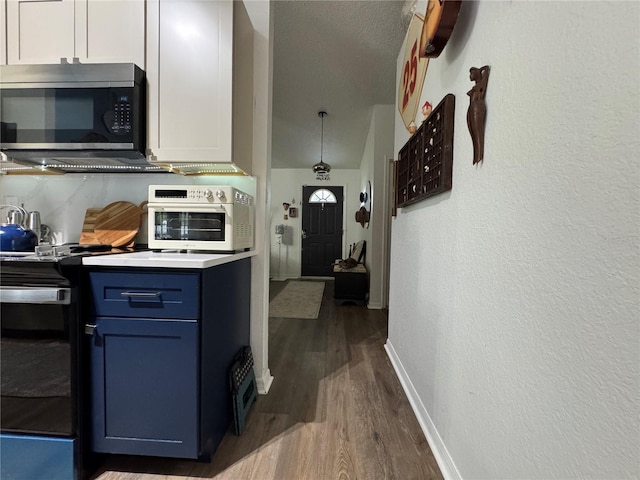 kitchen with stainless steel microwave, blue cabinetry, baseboards, dark wood-style floors, and electric range