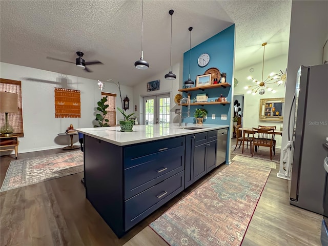 kitchen with wood finished floors, light countertops, vaulted ceiling, french doors, and appliances with stainless steel finishes