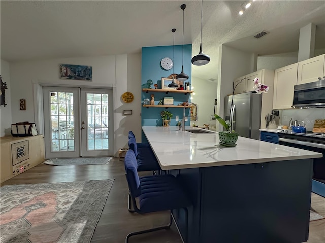 kitchen with visible vents, a breakfast bar, a sink, appliances with stainless steel finishes, and vaulted ceiling