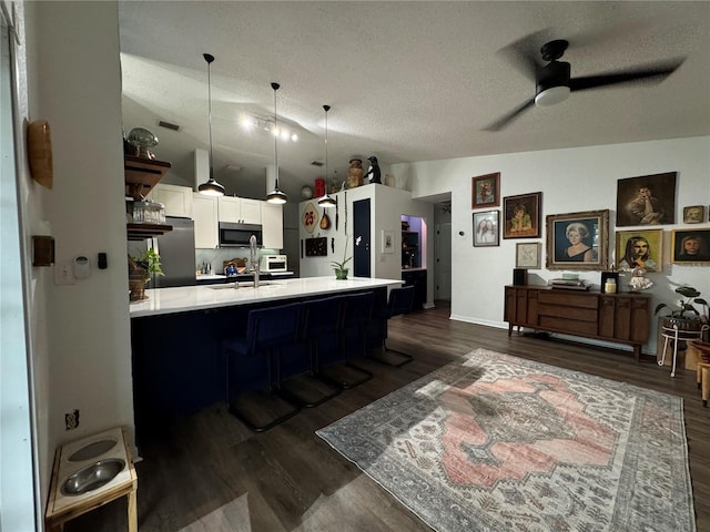 kitchen featuring dark wood finished floors, appliances with stainless steel finishes, white cabinetry, and light countertops